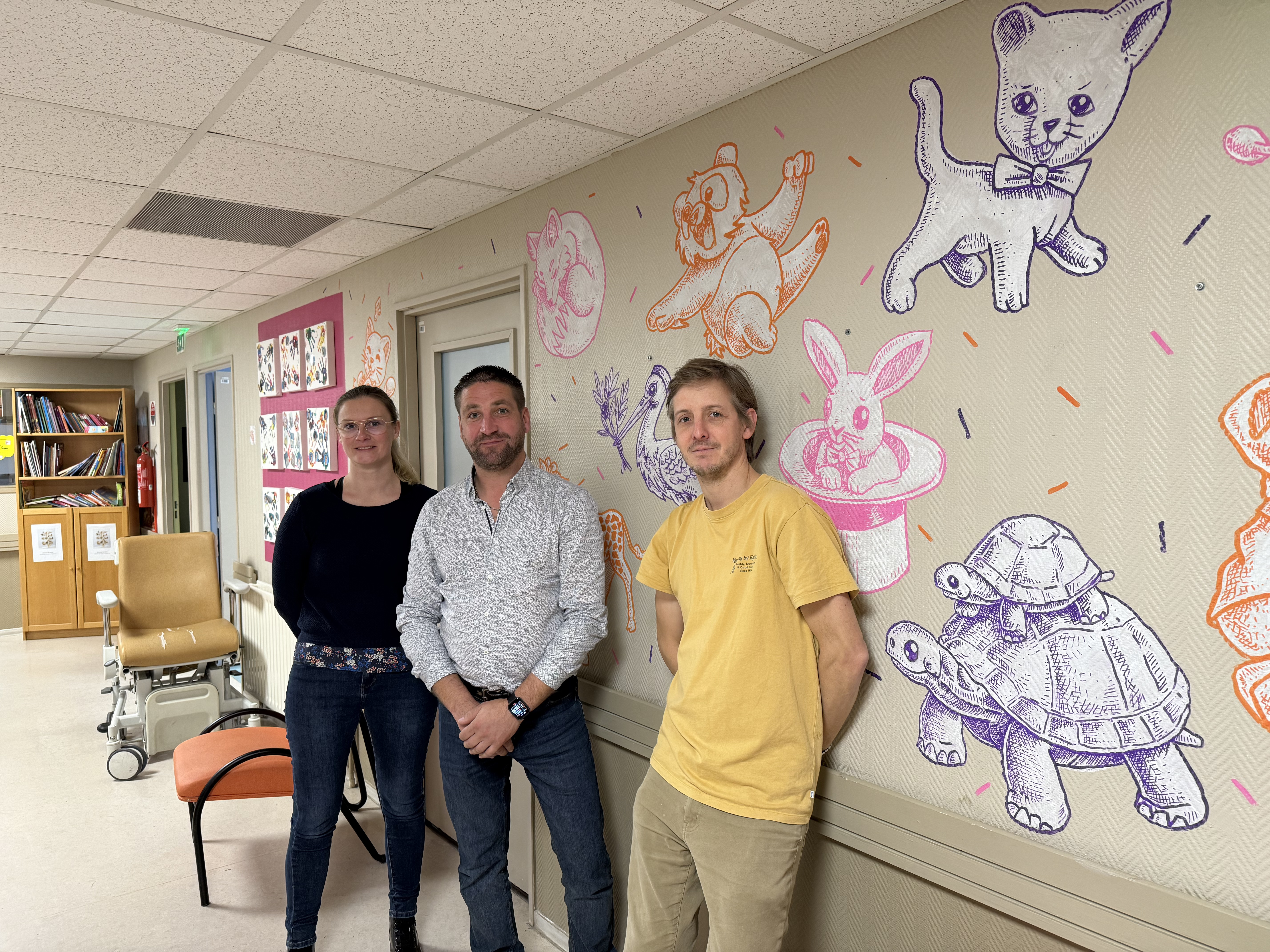 Deux membres de Hop We Care devant une fresque murale à l’hôpital